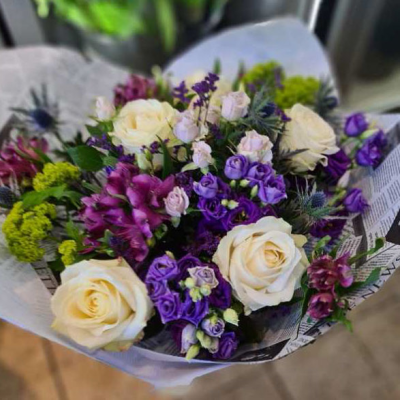 Cool Breeze - A charming hand-tied bouquet featuring cream roses, purple lisianthus, and seasonal greenery, suitable for various occasions.