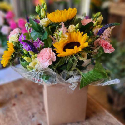 Bright and Bold - A vibrant arrangement in a box featuring sunflowers, pink carnations, and seasonal flowers, perfect for any joyous occasion. Florist Choice based on seasonal availability